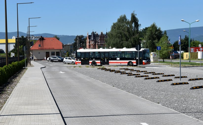 Duży parking przy cmentarzu, na końcu stojący autobus komunikacji miejskiej