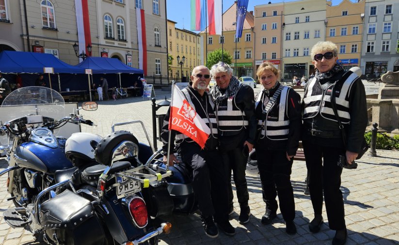 Czwórka motocyklistów w czarnych strojach, obok motory