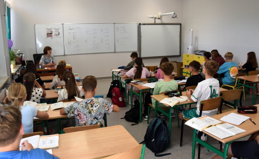 Ucnziowie podczas lekcji siedzący przy szkolnych ławkach