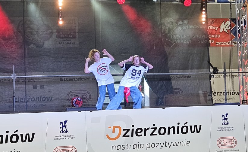 Dwie dziewczyny w białych koszulkach tańczące na scenie