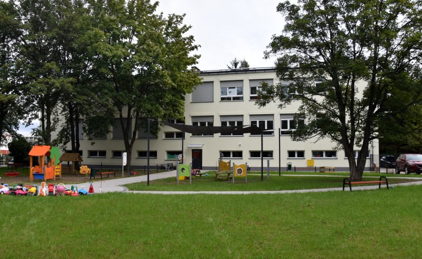 Dwupiętrowy budynek żłobka z nową piaskową elewacją, przed budynkiem plac zabaw
