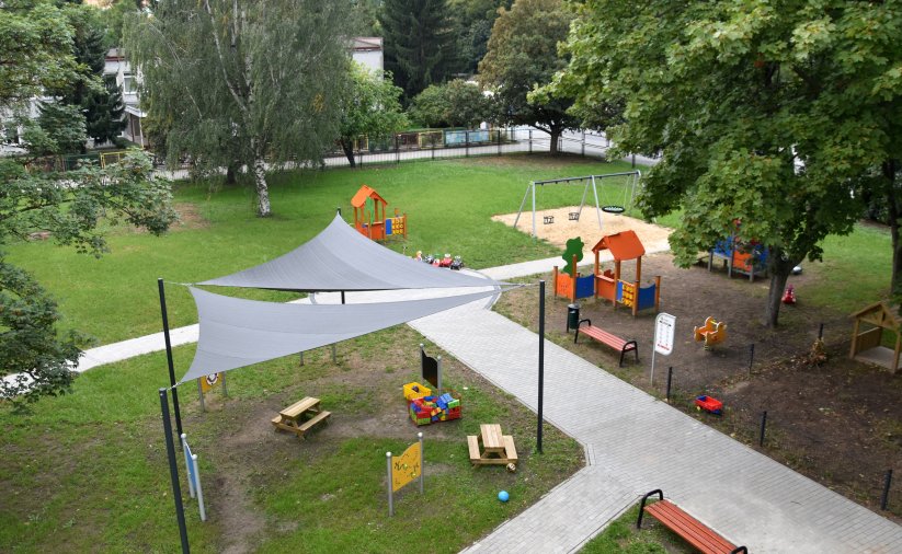 Pgród z placem zabaw dla dzieci, część zasłonięta płachtami dającymi cień
