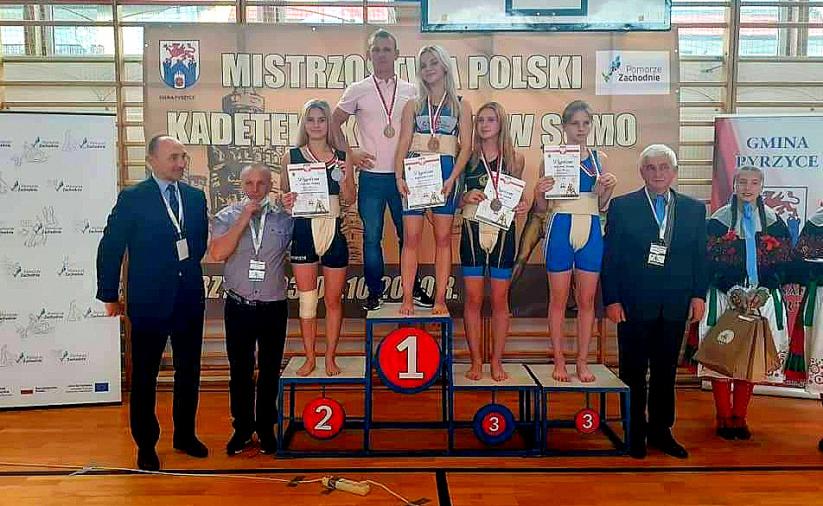 Zawodniczki z trenerami na podium medalowym