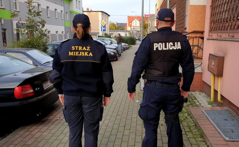 Strażnik miejski i policjant patrolujący razem ulice 