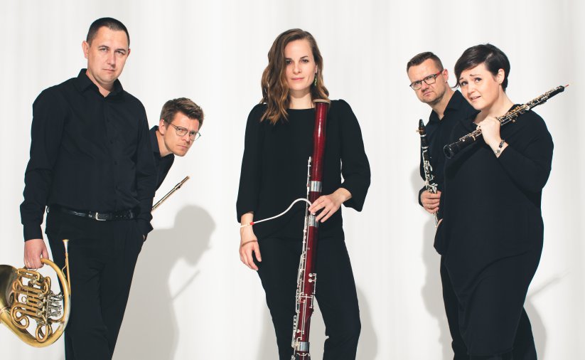 Pięcioro muzyków trzymających instrumenty w śroku kobieta, białe tło