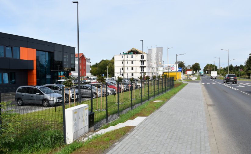 Chodnik z kostki, po lewej budynki i zieleń