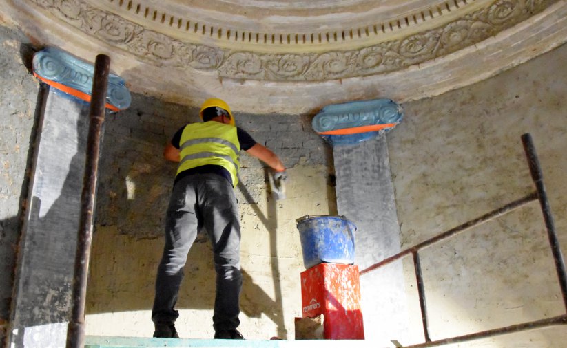 Wnętrze kaplicy, pracownik na rusztowaniu pracuje przy odestaurowaniu ściany