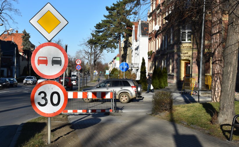 Widok chodnika i drogi, na pierwszym planie znaki drogowe