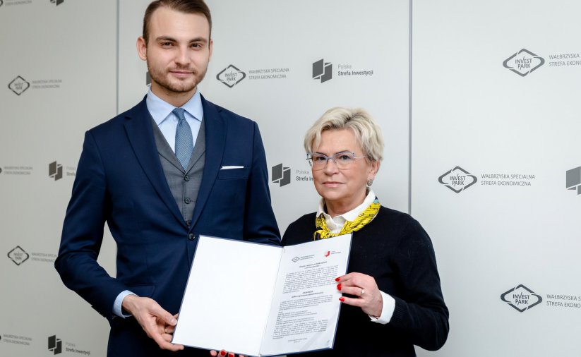 KObieta i mężczyzna trzymaja teczkę z dokumentami na tle ścianki Invest Park
