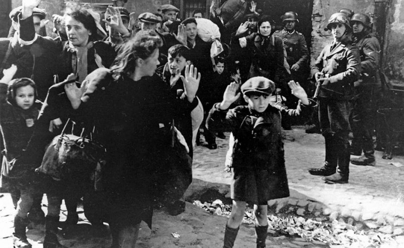 Zdjęcie archwiwalne, czarno-białe, przedstawia Żydów wypędzanych z mieszkań przez Niemców