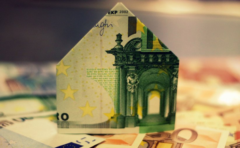 Banknot eur złozony w domek stojący na leżacych banknotach
