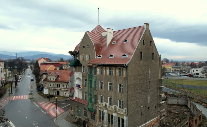 Zabytkowa komienica widziana z góry, w drugim tle miasto i góry