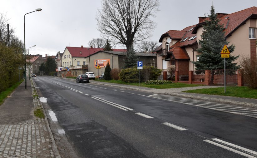 Pusta droga w mieście, deszczowa pogoda, po prawej stronie kamienice 