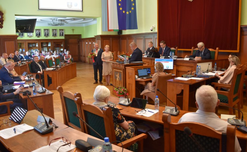 Sesja rady miejskiej, sala pełna osób siedzących rpzy stołach