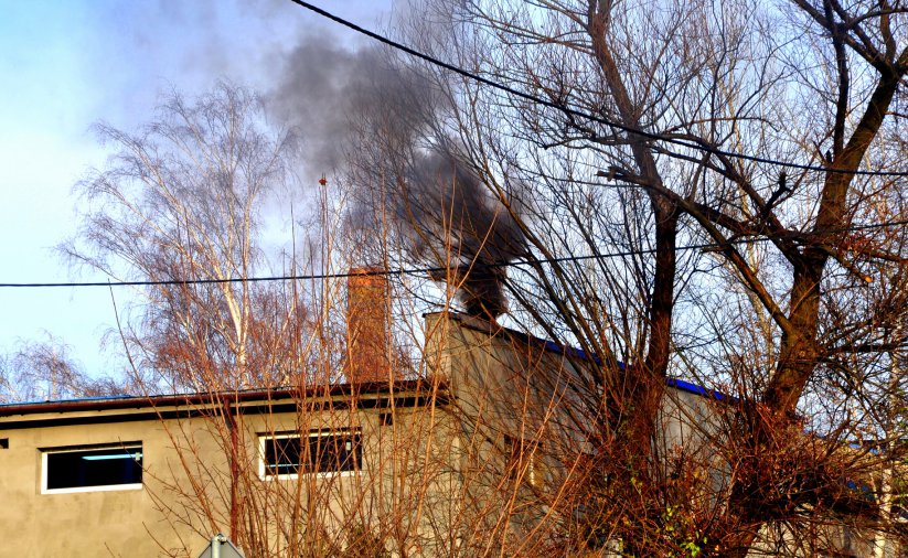 Dach budynku i czarny dym wydobywający się z komina