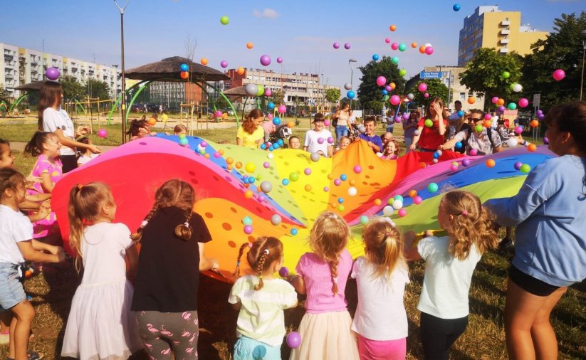 DFzieci bawiące się kolrową chustą i kolorowymi piłeczkami 