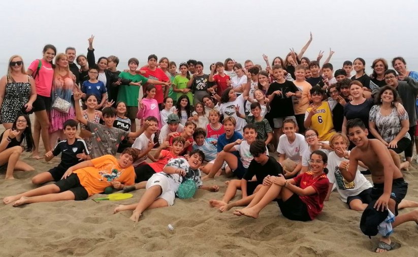 Kilkadziesiąt osób na grupowym zdjęciu na plaży 