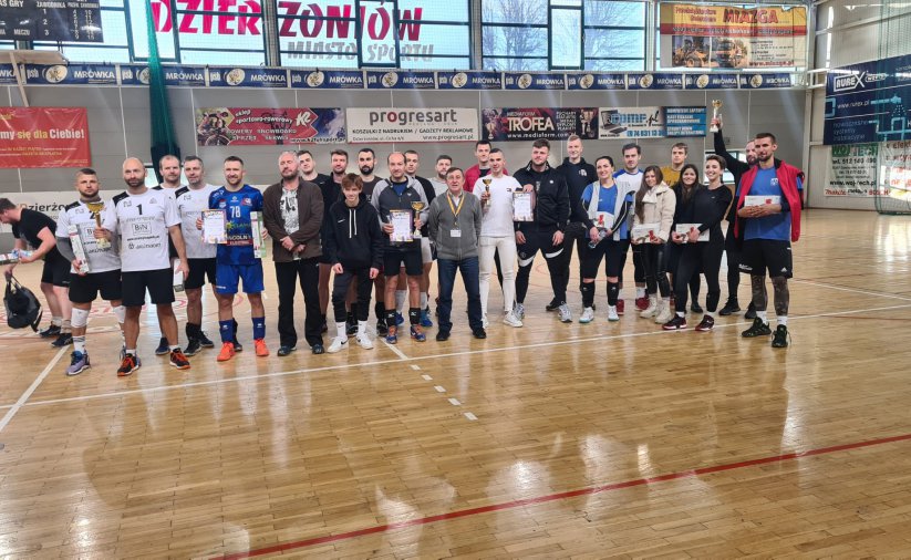 zawodnicy z pucharami w hali sportowej