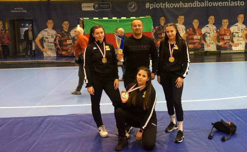 Trzy zwaodniczki z trenerem na macie zapaśniczej 