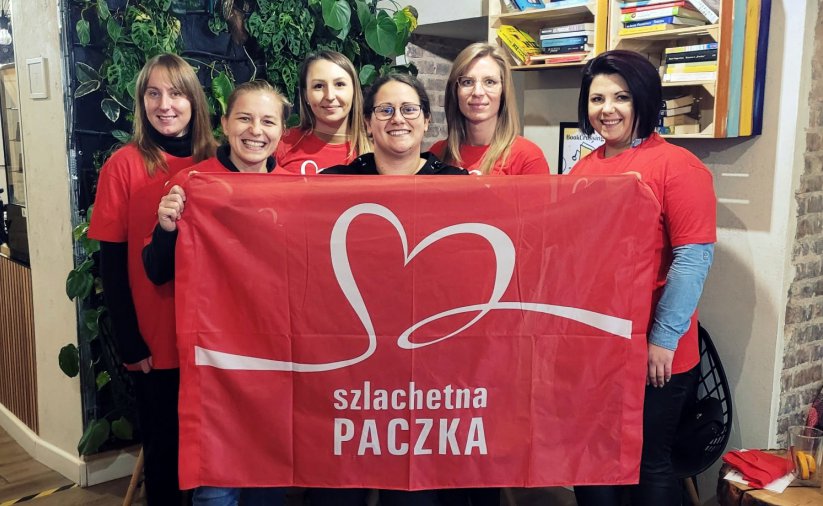 Sześć kobiet trzymających czerwoną flagę z napisem Szlachetna Paczka