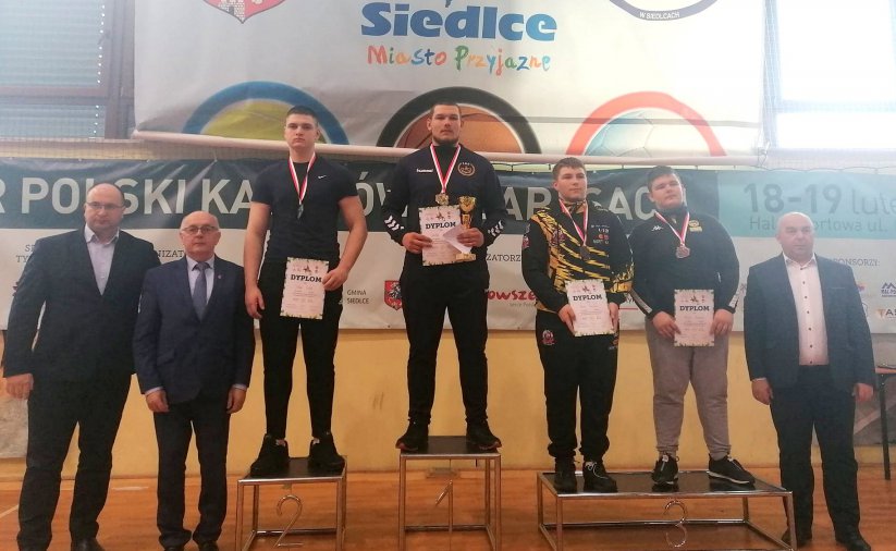 Zawodnicy z dyplomami na wspólnym zdjęciu na podium , obok trenerzy
