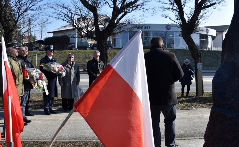 Falag Polski na pierwszym planie, w drugim pplanie grupa osób stojąca przy ulicy