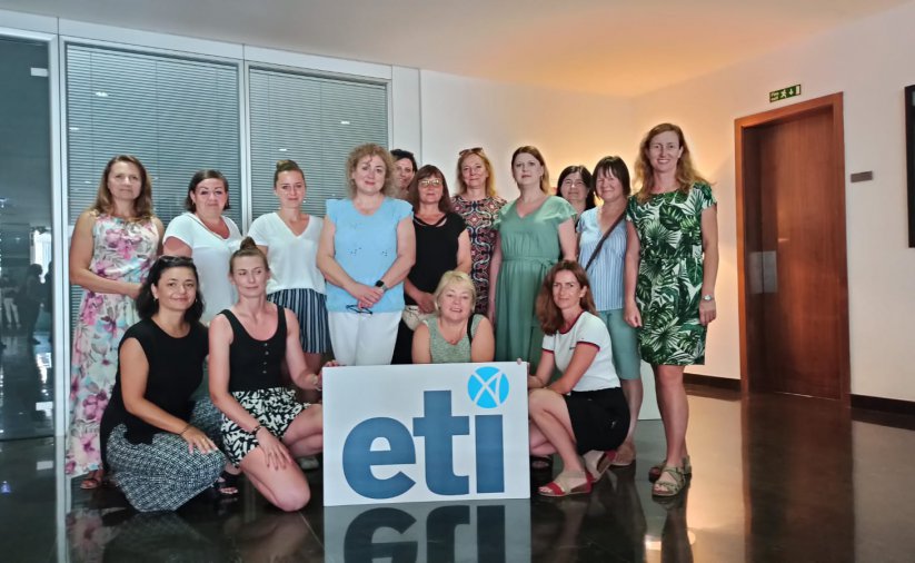 Grupa nauczycielek, trzyma tablicę z logotypem ETI