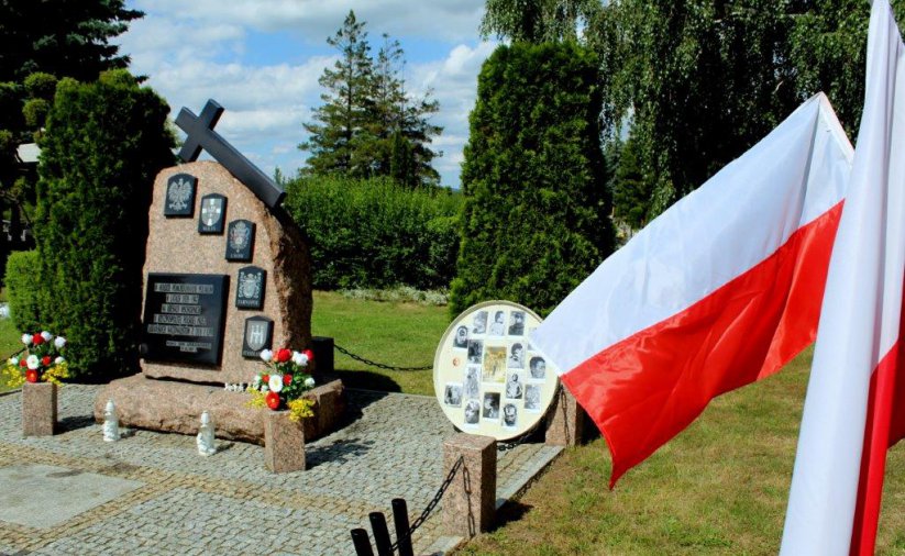 Kamienny obelisk na cmentarzu i flaga Polski