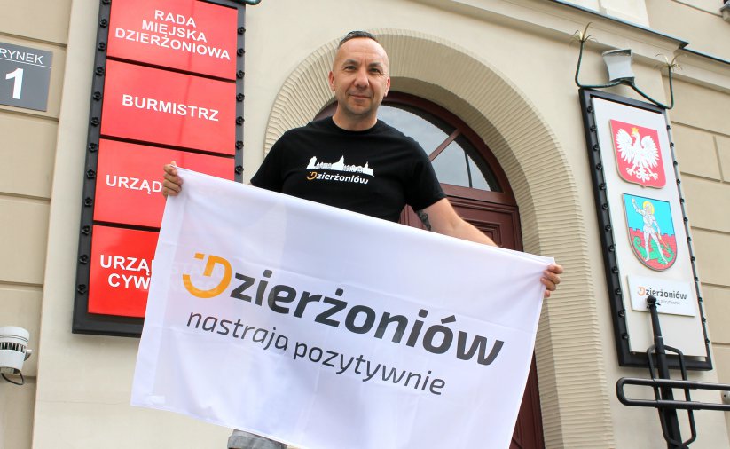 Mężczyzna przed wejściem do ratusza z banerem z napisem Dzierżoniów