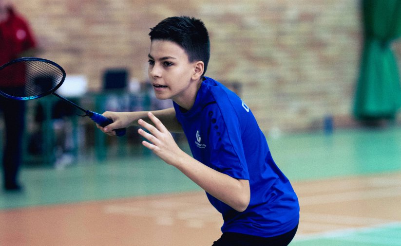 Chłopiec w ciemnoniebieskej koszulce z rakieta do badmintona