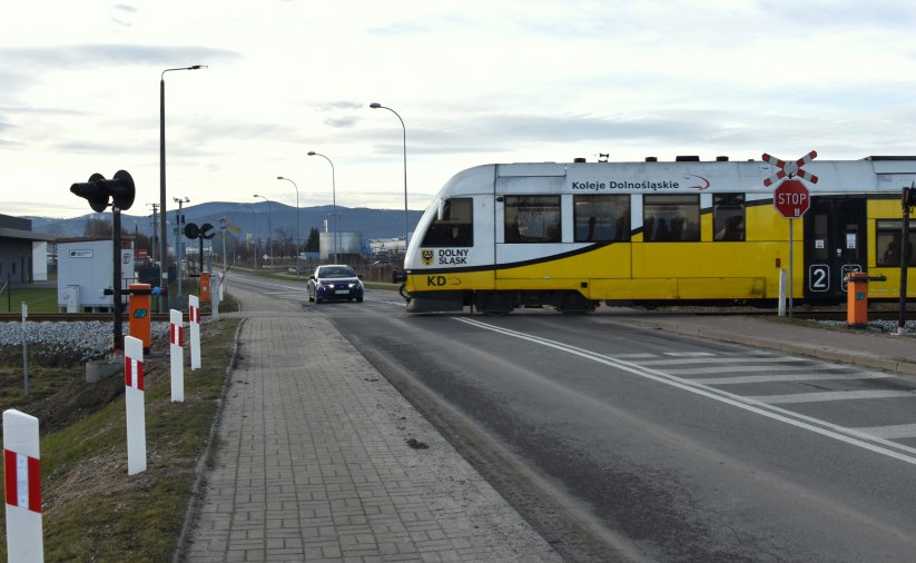 Szynobus, za nim samochód osobowy, w tle góry