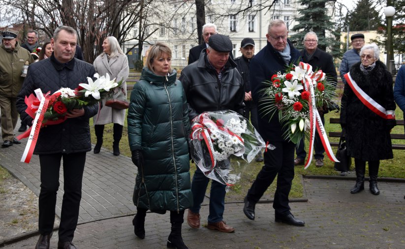 Grupa osób składająca wieńce przed pomnikiem