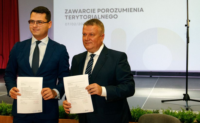 Dwóch mężczyzn w garnituracj trzymających przed sobą dokumenty