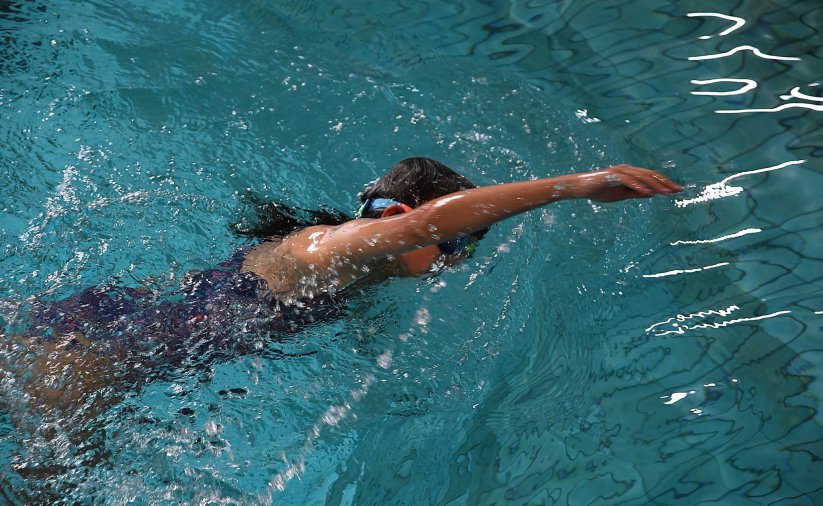 Dziewczyna podczas pływania, z wysunięta do przodu ręką. Zdjęcie z góry 