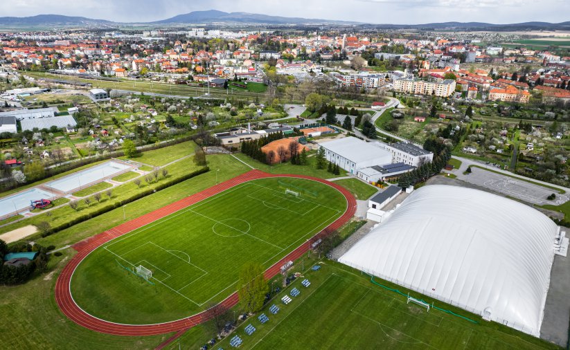 Boiska i hale sportowe widzine z głóry w drugim planie odkryte baseny io panorama miasta