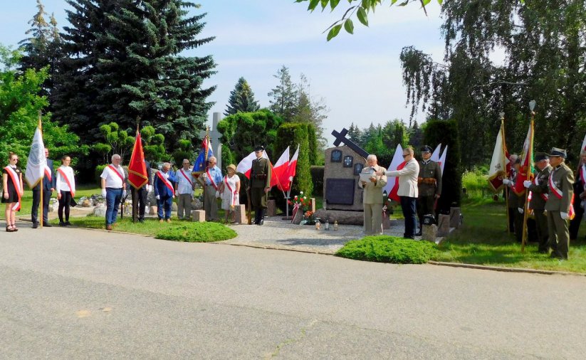 Cmentarny obelisk, ludzie z flagami Polski, żołenierze i kombatanci w mundurach 