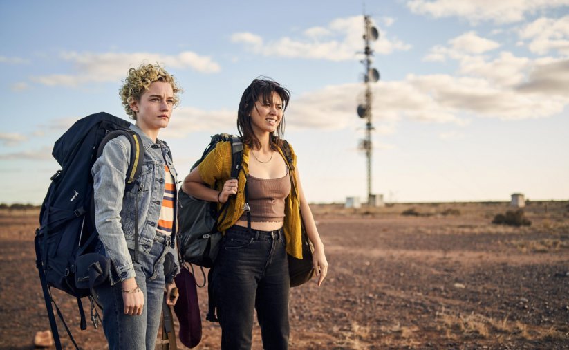 Kadr z filmu, dwie dziewczyny z plecakami turystycznymi, za nimi pustynny krajobraz