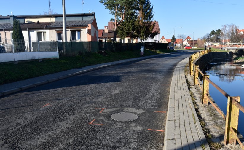 Droga asfaltowa, po lewej stronie rzeka, po prawej budynki