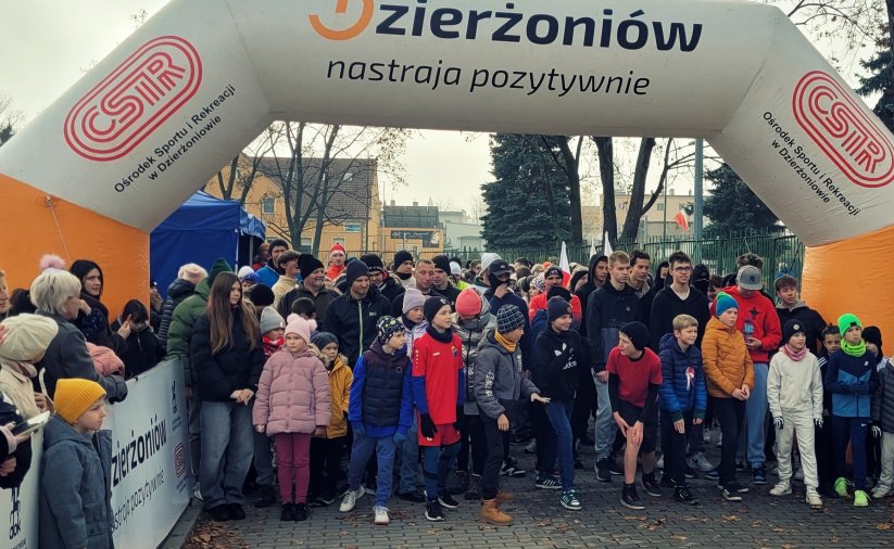 Kilkadziesiąt osób w róznym wieku na starcie wyścigu, u góry napis Dzierżoniów Nastraja Pozytywnie