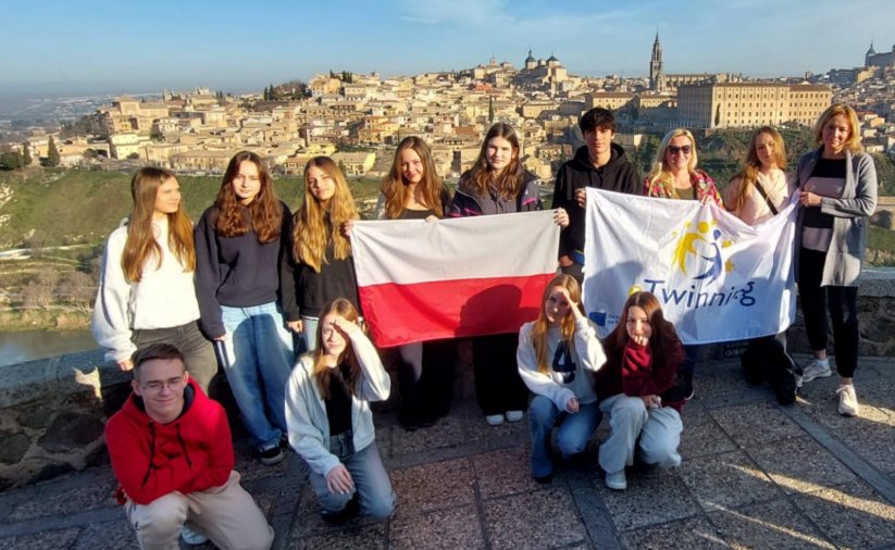 Grupowe zdjęcie uczniów SP9 z flagą Polski na tle panoramy zabytkowej starówki