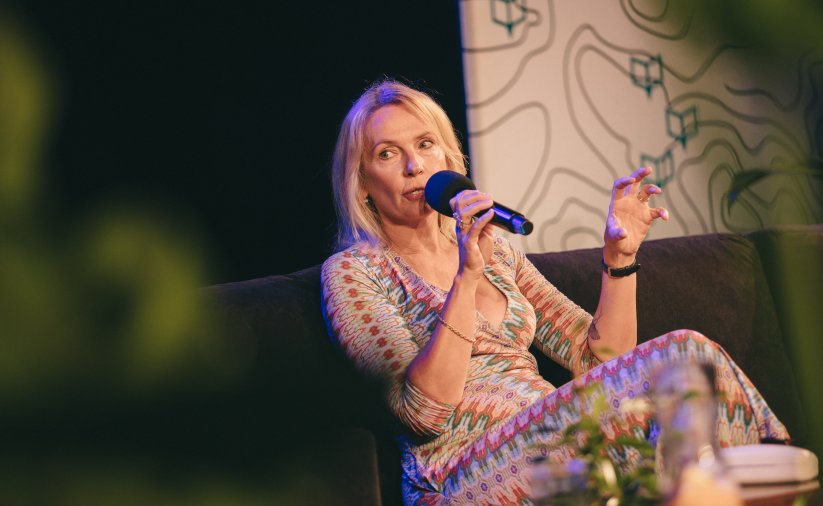 Pisarka Joanna Bator siedząca na krześle z mikrofonem w ręku w kolorowej sukience