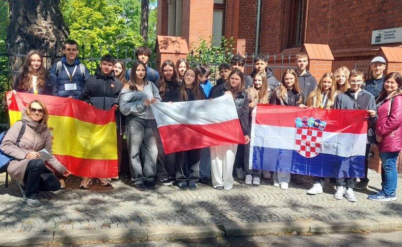Grupowe zdjęcie uczniów trzymających flagi Polski, Chorwacji i Hiszpanii