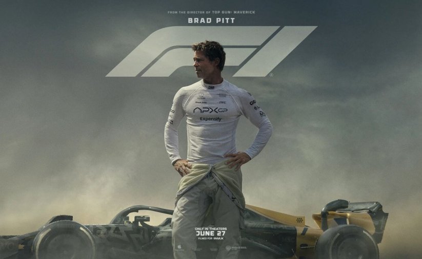 Mężczyzna w białej koszulce, za nim bolid formuły F1