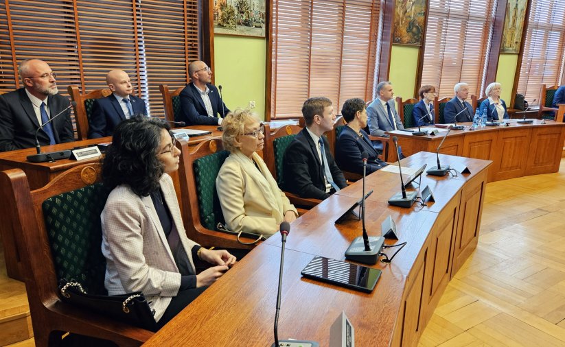 Radni przy stołach zmikrofonami podczas sesji
