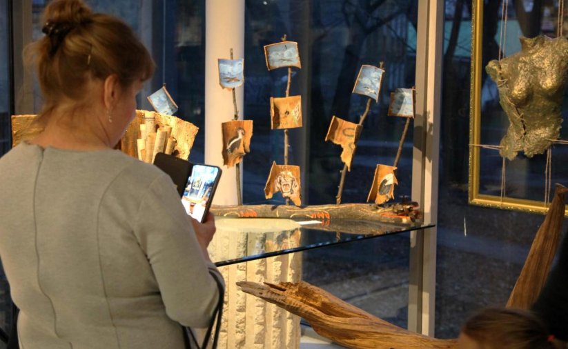 Kobieta z telefonem z dłoni robiąca zdjęcie artystycznej rzeźby