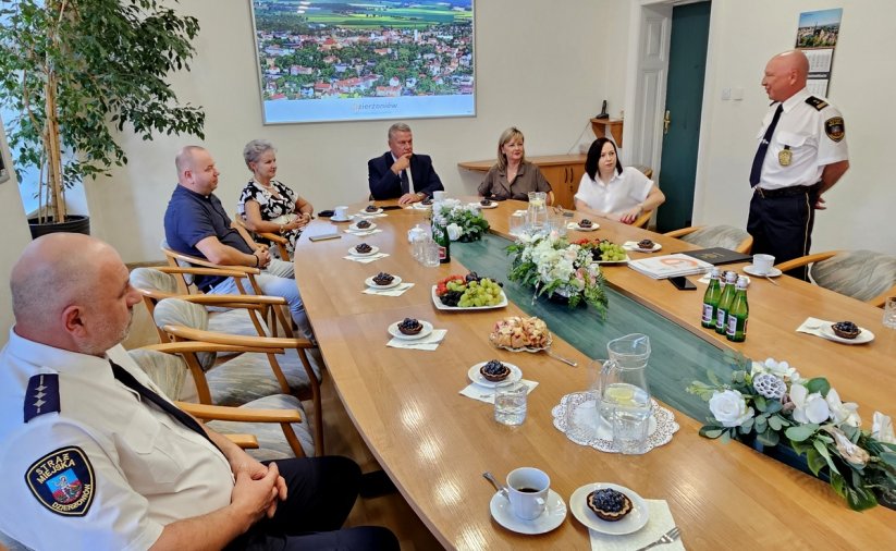 Zdjęcie strażników miejskich siedzących przy stole na spotkaniu z burmistrzem