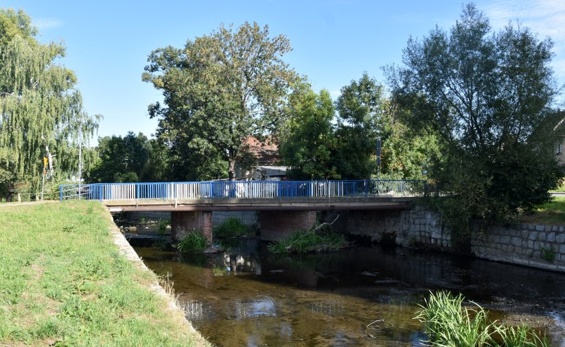 Most nad rzeką Piławą, po bokach i za mostem duże drzewa