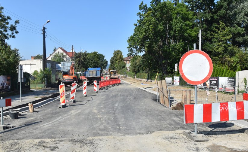 Droga w czasie remontu, poustawiane znaki ostrzegawcze, w tle auta ciężarowe i maszyny budowlane
