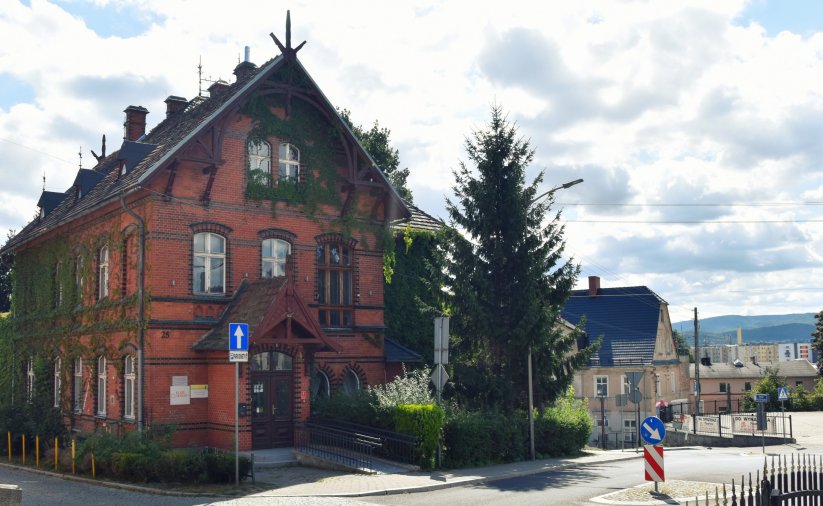 Zabytkowa kamienica z czerwonej cegły, jedna ze ścian częściowo porośnieta bluszczem
