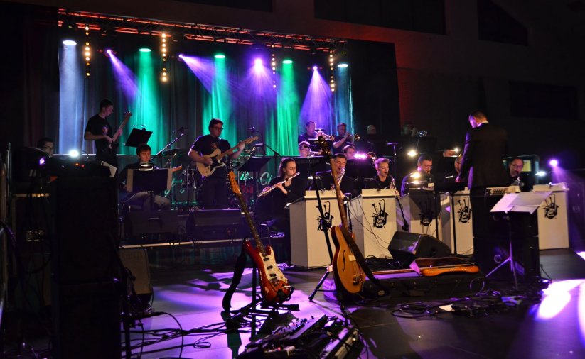 Muzycy Big Roll Band na oświetlonej scenie, pzred nimi dyrygent i instrumenty